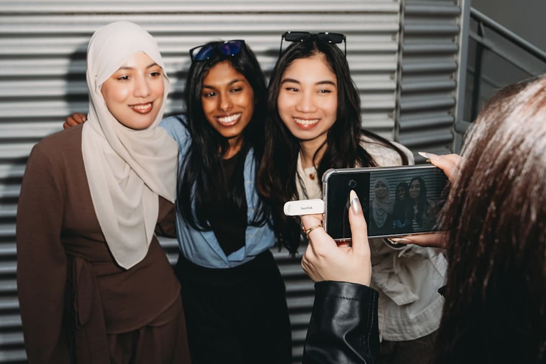 Tres mujeres jóvenes sonríen mientras miran un smartphone, en la sala de chat de Jóvenes