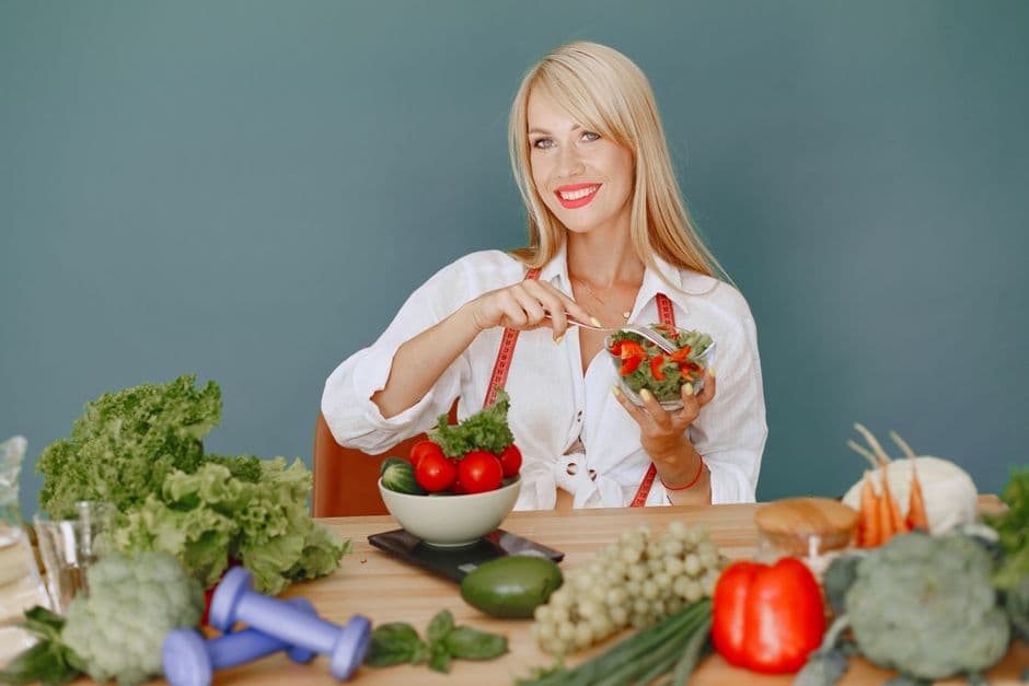 Mujer sentada tras mesa verduras, sostiene cuenco de ensalada, en la sala de chat de Nutrición