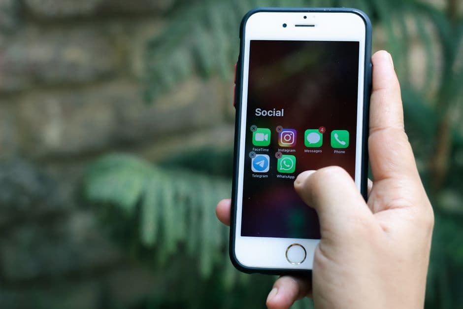 Mano sosteniendo iPhone blanco con funda negra, en la sala de chat de Fútbol Telegram