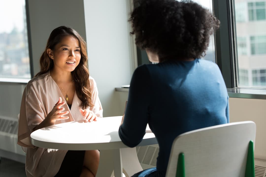 Dos mujeres sentadas en una silla, conversando animadamente, en la sala de chat de Debate