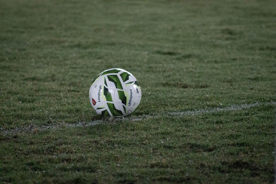 Balón de fútbol sobre césped verde bajo luz nocturna, en el chat de Real Betis