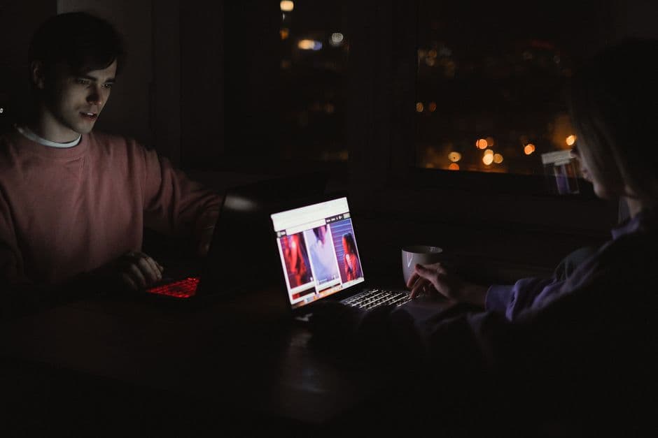 Jóvenes sentados frente a portátiles en una habitación oscura, en la sala de chat de Canalchat