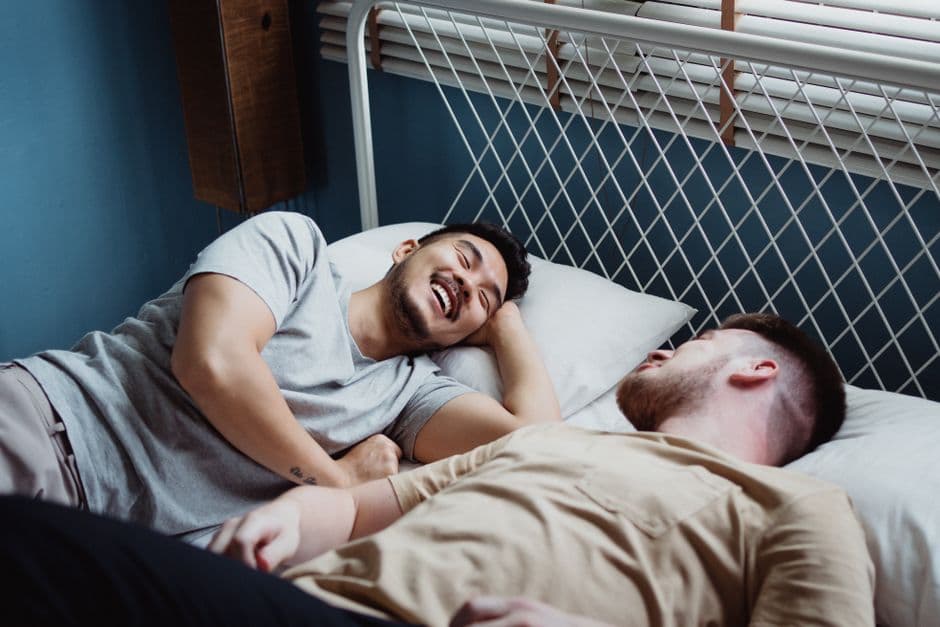 Pareja gay sonriendo juntos en un momento íntimo, en la sala de chat de Clubgay