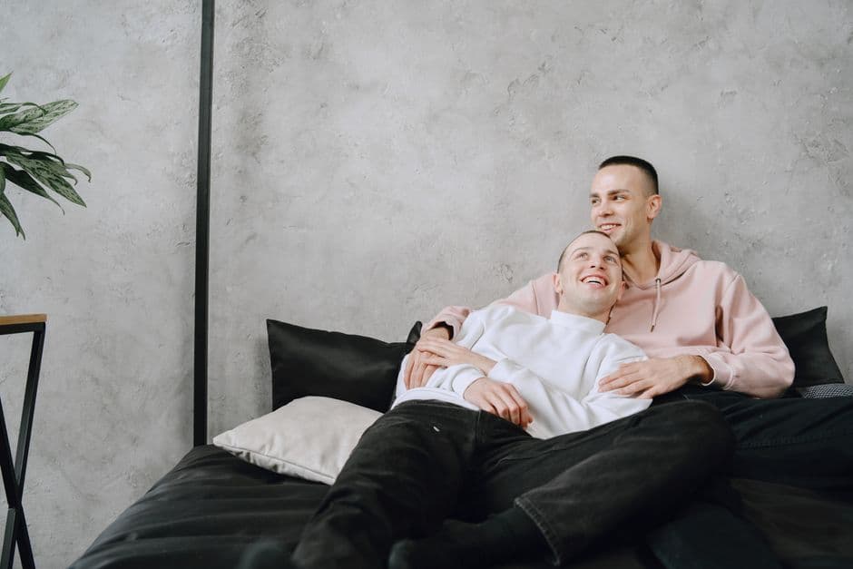 Dos hombres sonrientes acostados en la cama, en la sala de chat de Chat Gay Euskadi