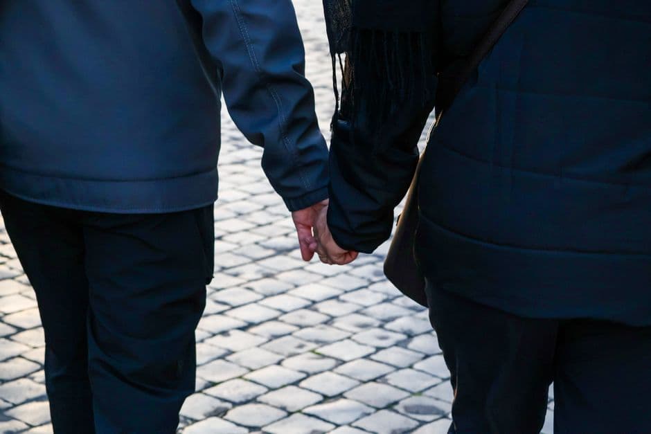 Dos personas caminando por calle tomadas de la mano