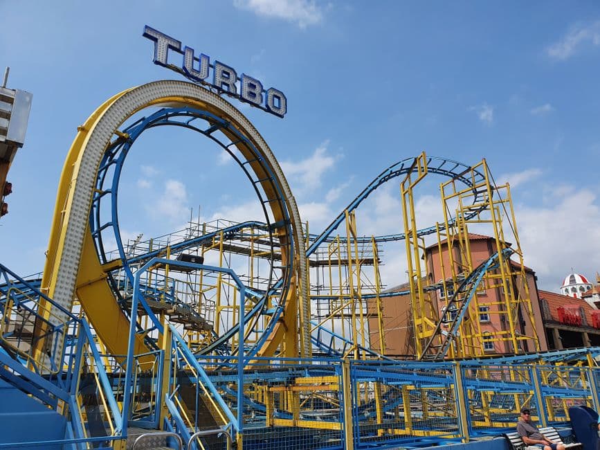 Una montaña rusa en pleno recorrido en un parque de atracciones