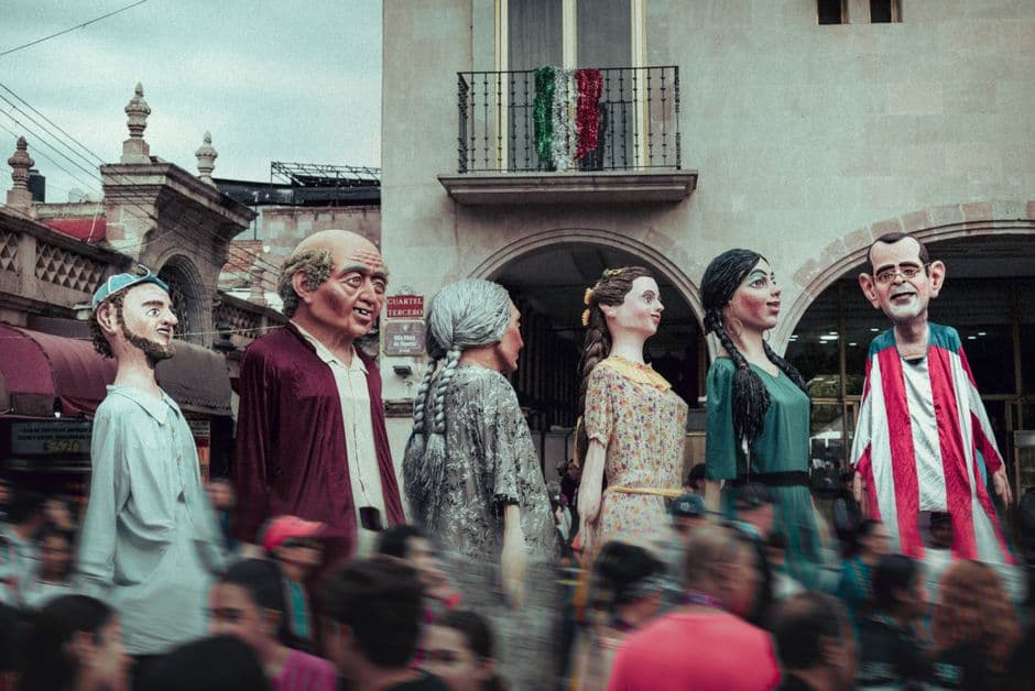 colorful parade with giant puppets on busy street