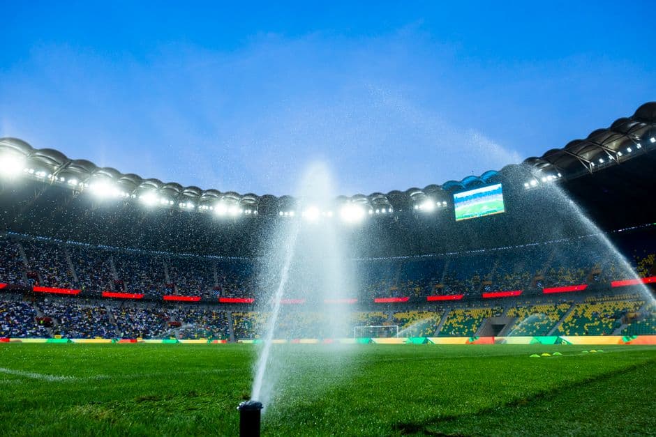 Aspersores regando el césped de un estadio de fútbol de noche