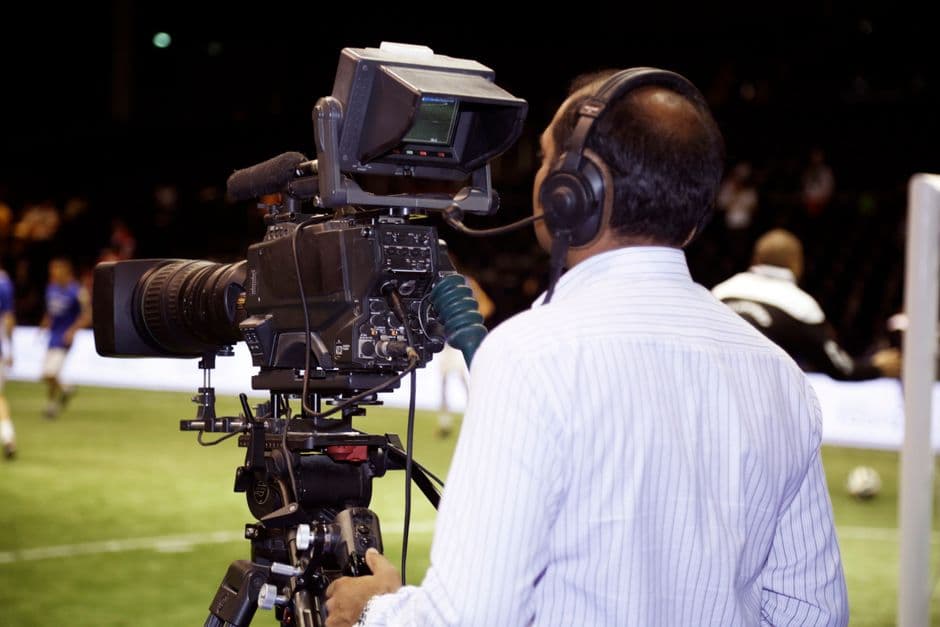 Un hombre con una cámara de televisión grabando un partido de fútbol