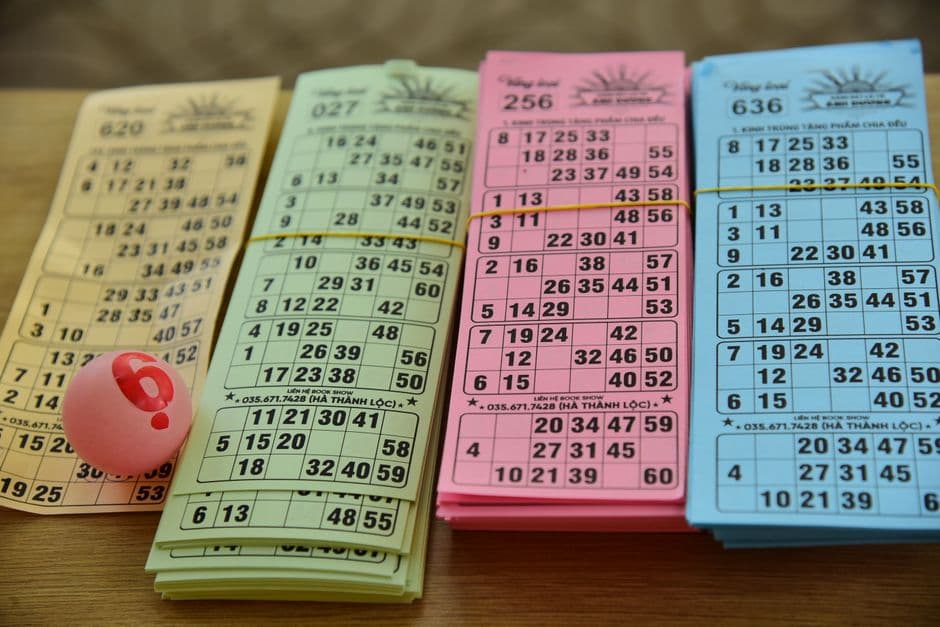 Cartones de bingo de colores y una bola numerada sobre una mesa