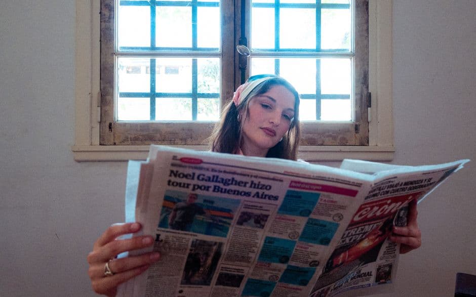 Una joven leyendo el periódico junto a una ventana