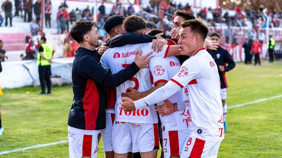Un equipo de fútbol celebrando un gol en un partido al aire libre
