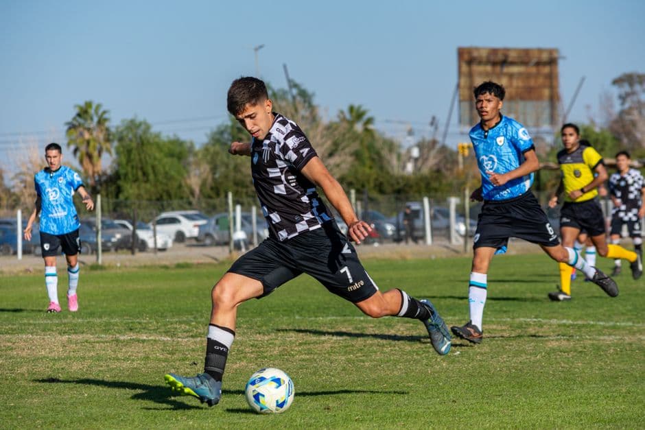 Jóvenes futbolistas compitiendo por el balón en día soleado