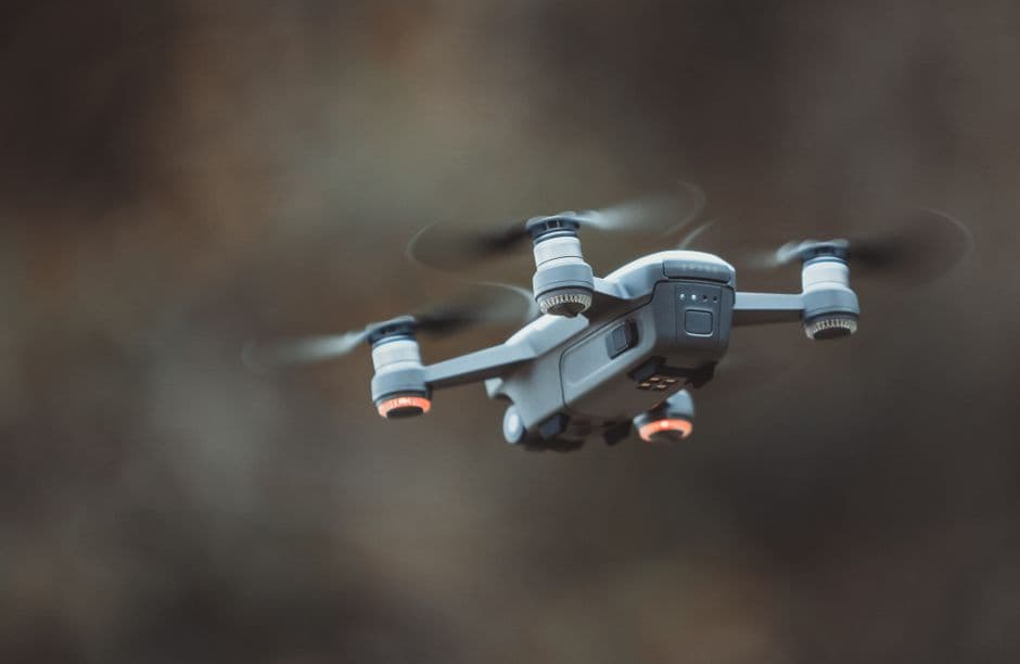 Dron gris de cuatro hélices volando en el aire