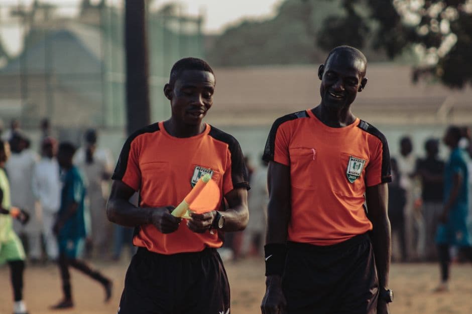 Árbitros de fútbol en camisetas naranjas en el campo