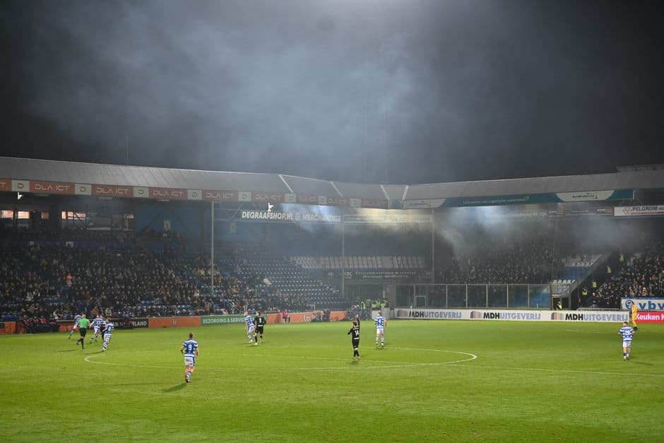 Estadio de fútbol con jugadores entrenando al anochecer