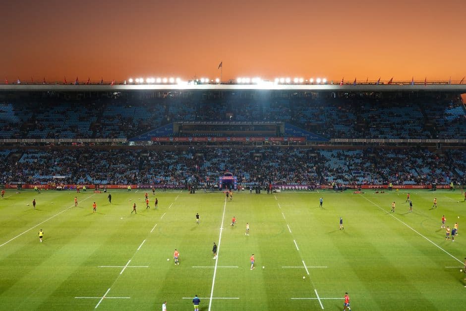 Partido de rugby vibrante al atardecer en un estadio