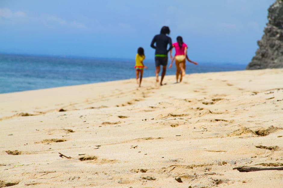 Hombre, mujer y niña caminando junto a la costa marina