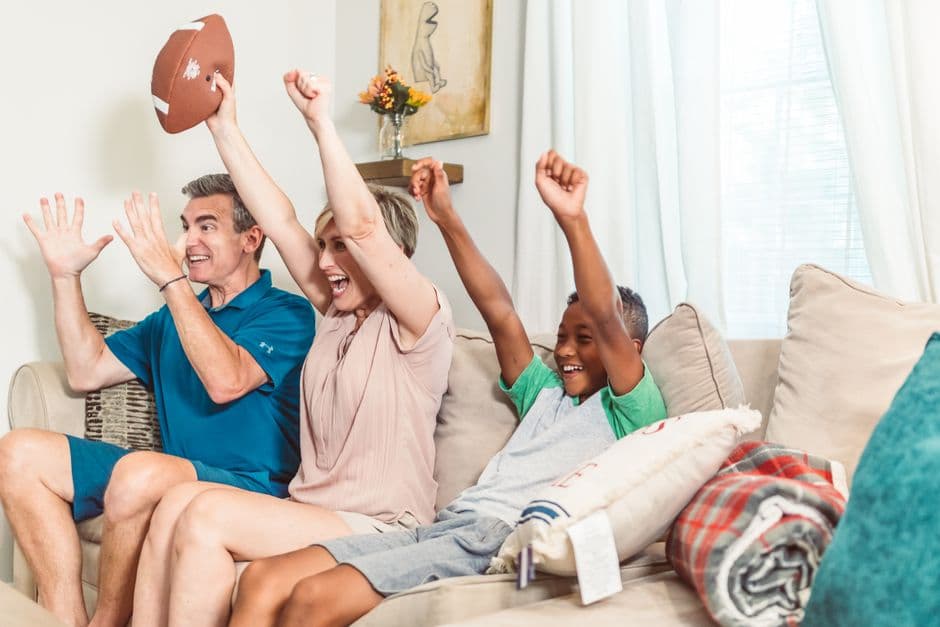 Familia feliz en sofá animando juntos durante evento deportivo