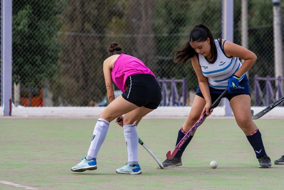 Mujeres jugando hockey sobre hierba en cancha al aire libre