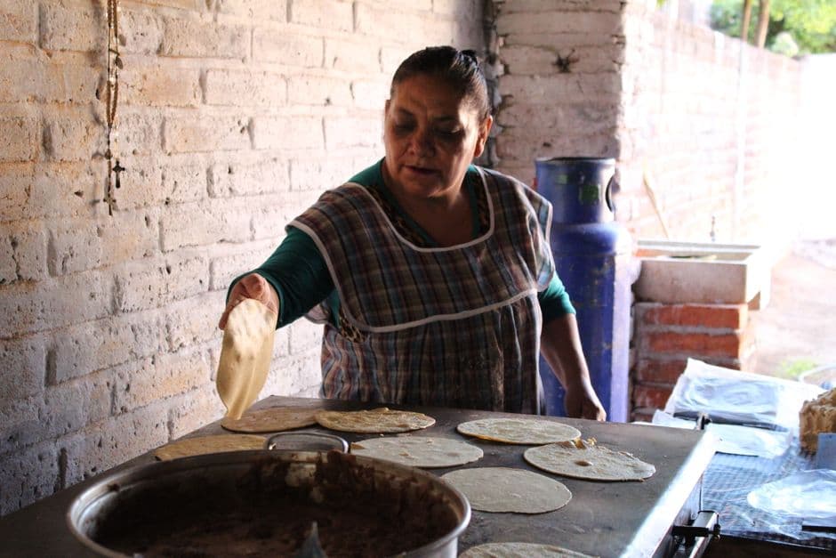 Mujer preparando tortillas en la cocina tradicional mexicana