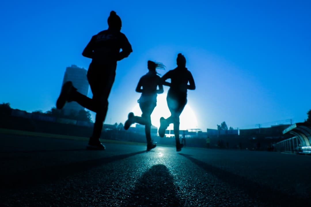 Silueta de tres mujeres corriendo en una carretera gris