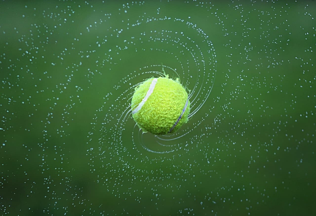 Una pelota de tenis en movimiento rotatorio en la pista