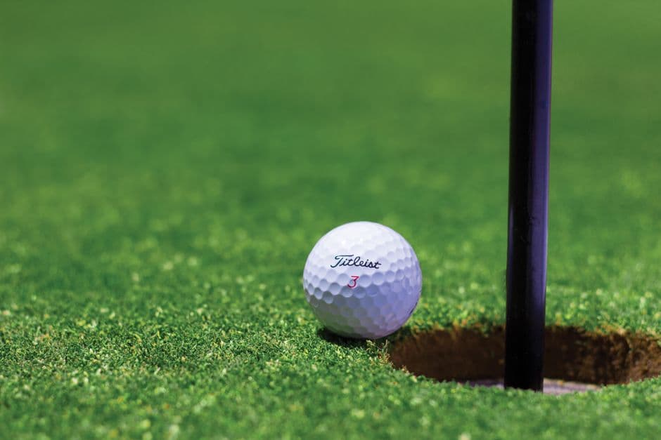 Una pelota de golf junto a un hoyo en el terreno de juego