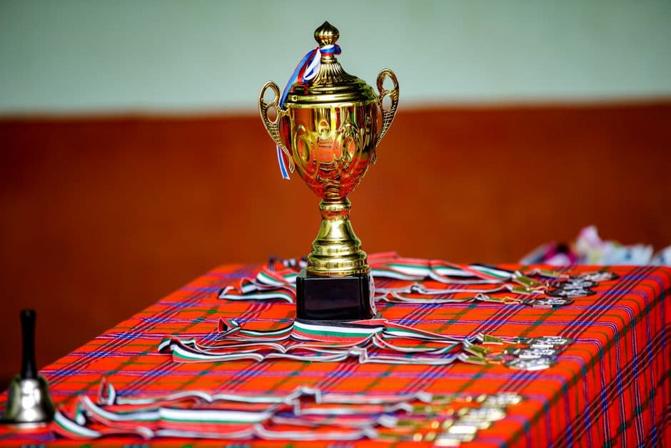 Trofeo de oro y medallas sobre mesa con mantel a cuadros