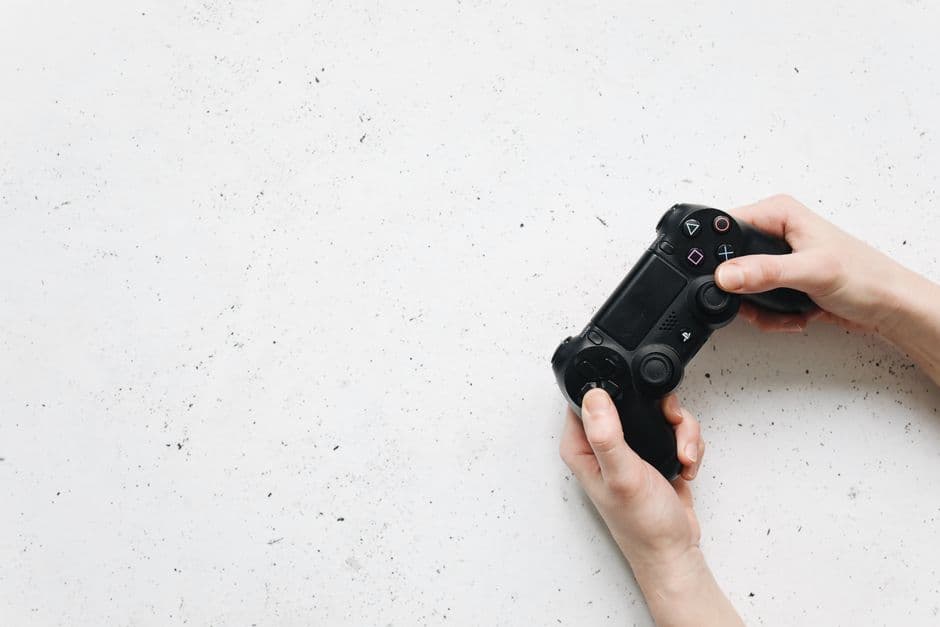 Manos sosteniendo un controlador de videojuego de color negro