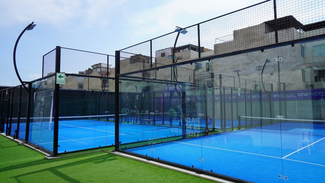 Cancha de tenis rodeada por una cerca metálica bajo cielo despejado