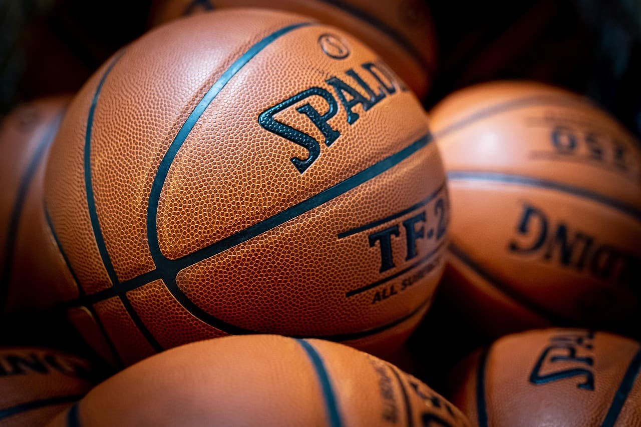Balón de baloncesto Spalding sobre superficie de madera, con costuras negras visibles