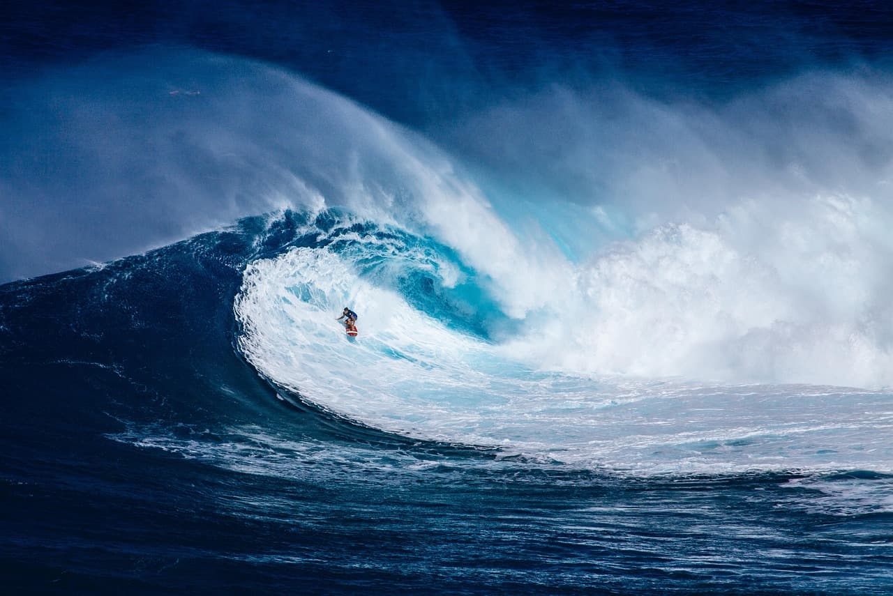 Surfista cabalgando una ola grande bajo un cielo azul en el océano