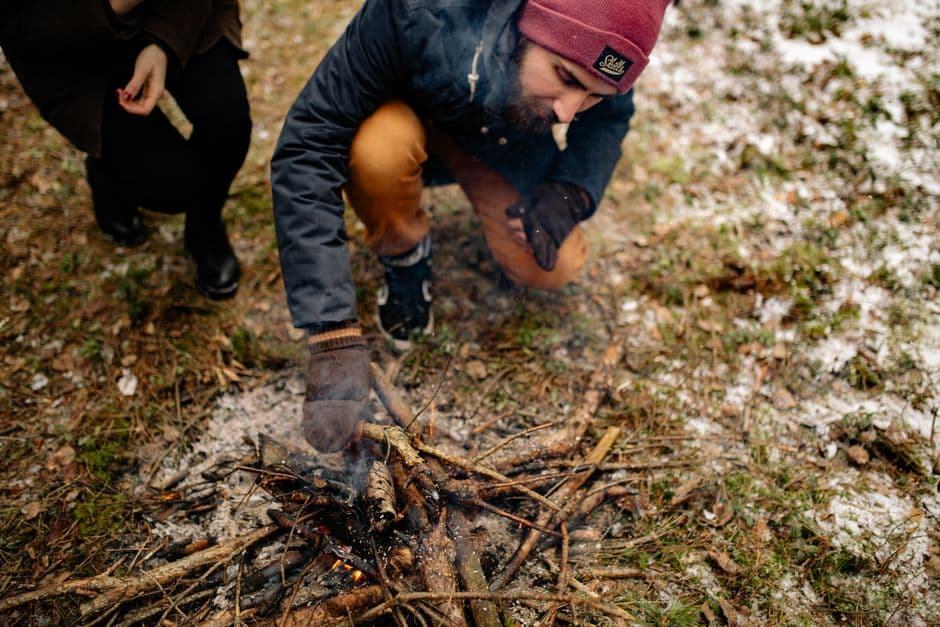 Personas encendiendo una fogata en el suelo invernal