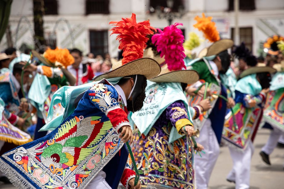 Mujeres y hombres bailan en coloridos trajes tradicionales con cintas y sombreros