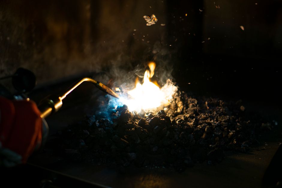 Carbón incandescente ardiendo bajo la llama de una antorcha de soldadura