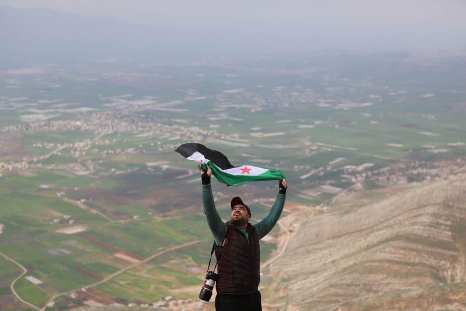 Un hombre sosteniendo una bandera en un valle de montaña