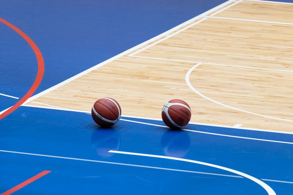Dos jugadores en una cancha cubierta de baloncesto azul