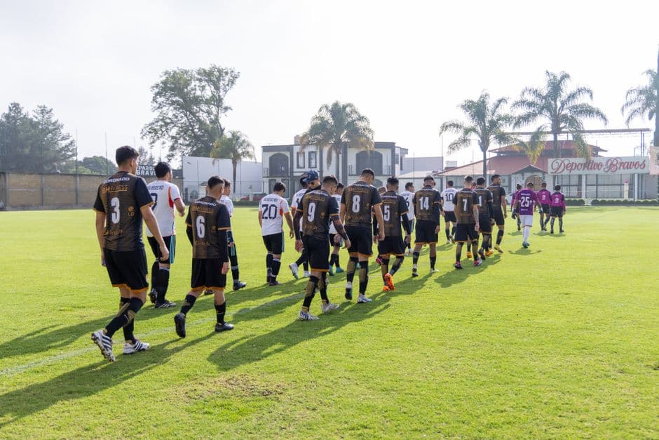 Equipos de futbolistas caminando sobre el terreno de juego