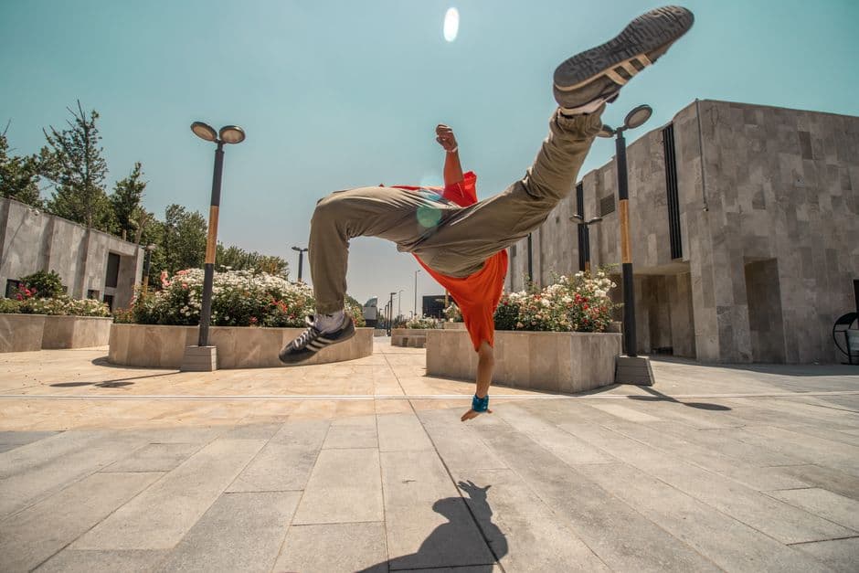 Un hombre haciendo un mortal de breakdance en una plaza