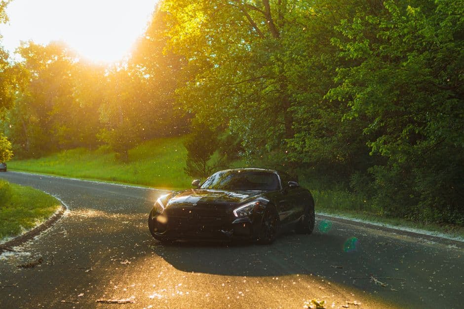 Un coche deportivo negro circula por una carretera al atardecer, en el chat de Motor