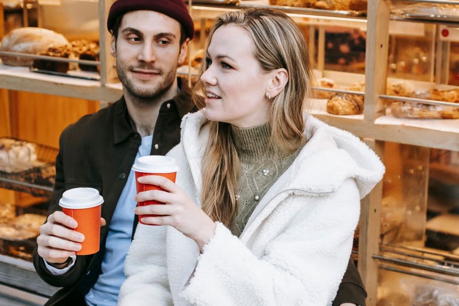 Pareja joven sonriendo mientras charlan en un café, en la sala de chat de Ligar