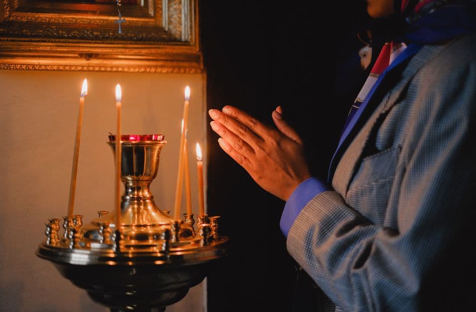 Manos unidas en oración con una vela encendida, en la sala de chat de Religión