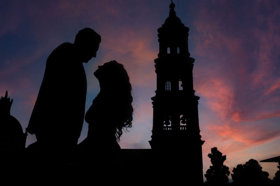 Pareja silueta frente a torre de iglesia al atardecer, en la sala de chat de Adultos