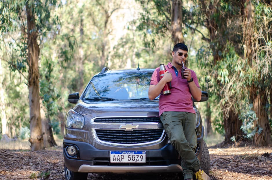 Hombre bebiendo mientras se apoya en su coche, en el chat de Canelones