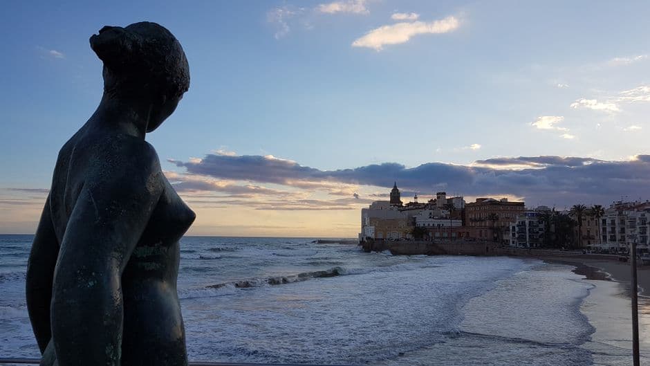 Estatua frente al mar de Sitges al atardecer, en el chat de Sitges