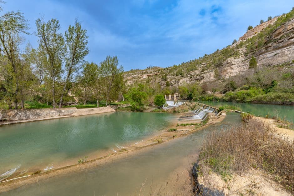 Paisaje fluvial sereno con montañas y árboles, en la sala de chat de La Garriga