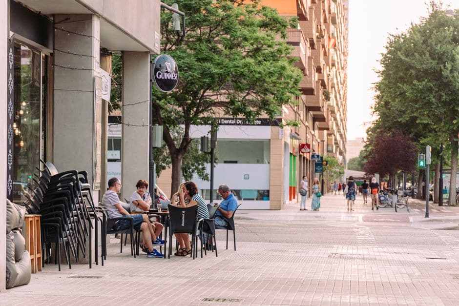 Personas sentadas en mesas en la acera de una ciudad, en el chat de Gernika-Lumo