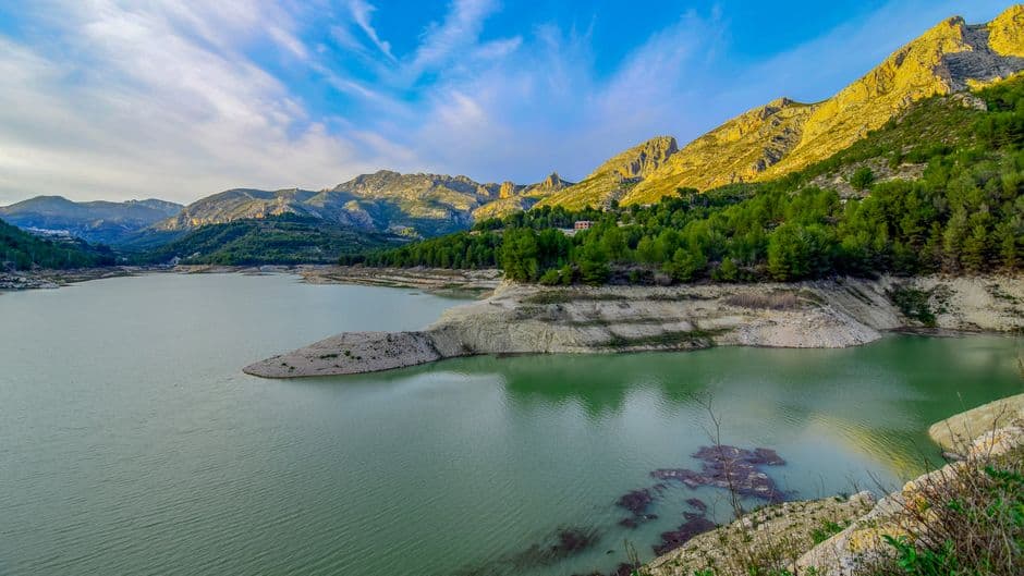Un lago rodeado de montañas bajo cielo azul, en el chat de Alginet