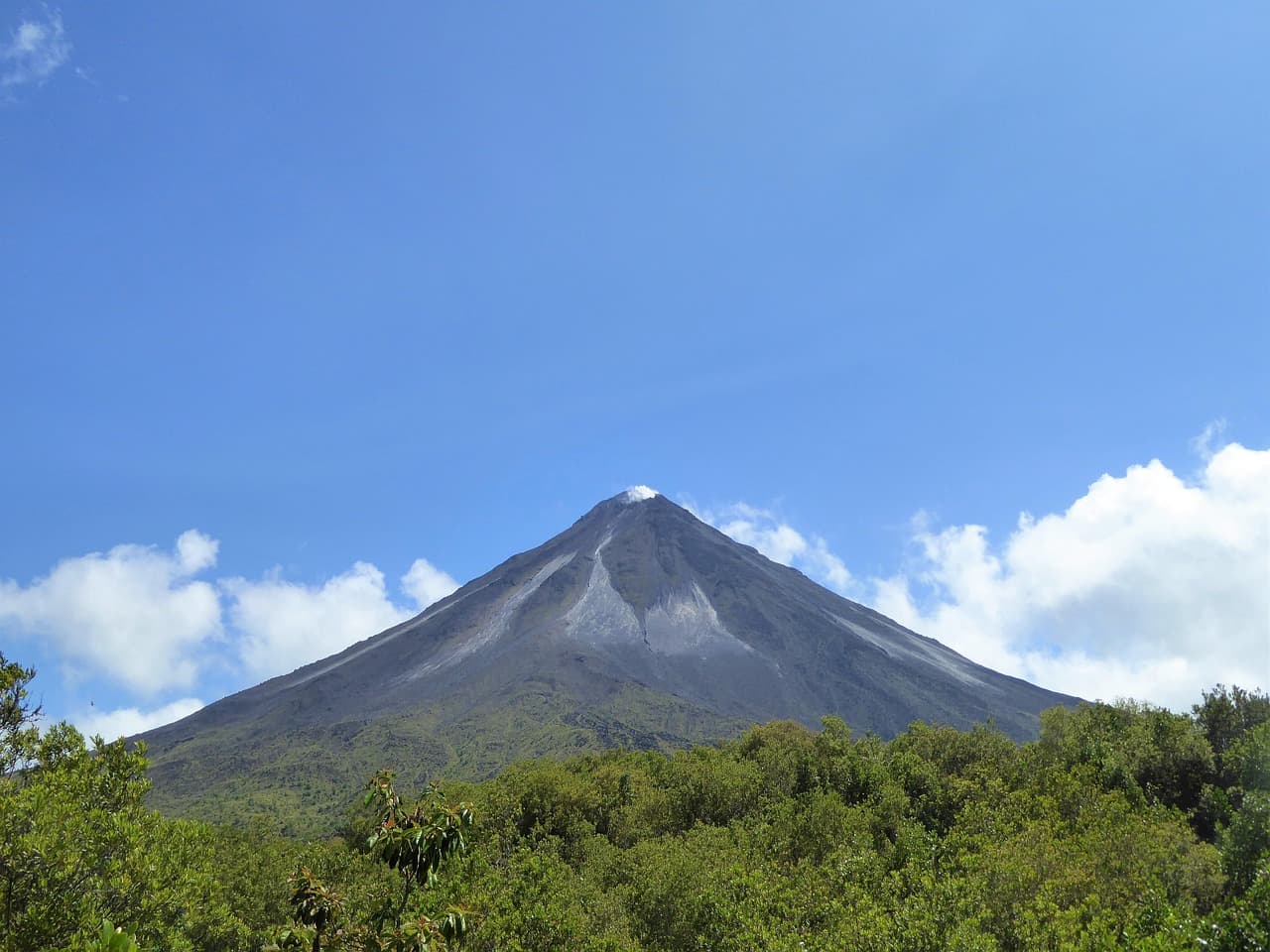 Volcán activo rodeado de vegetación tropical bajo cielo despejado, en el chat de Costa Rica
